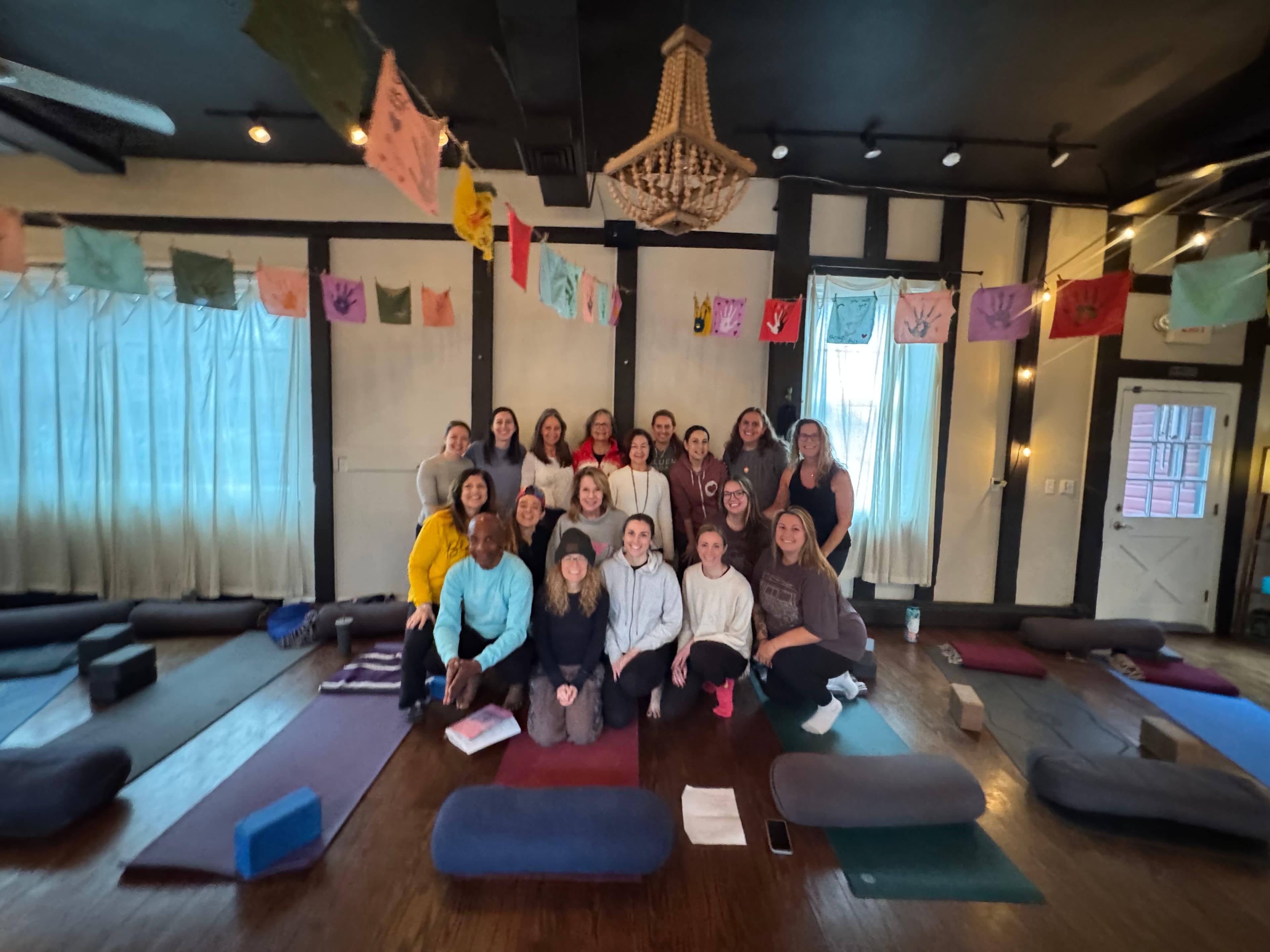Group yoga class photo with students on mats in a decorated studio